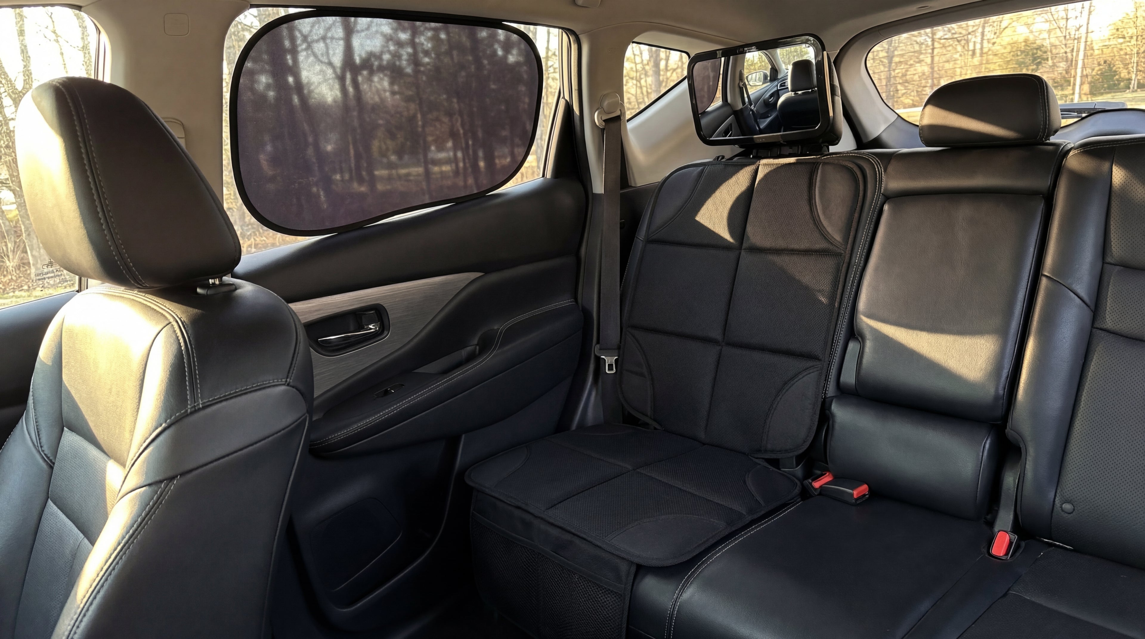 Backseat of a car with black leather seats in a sunlit setting