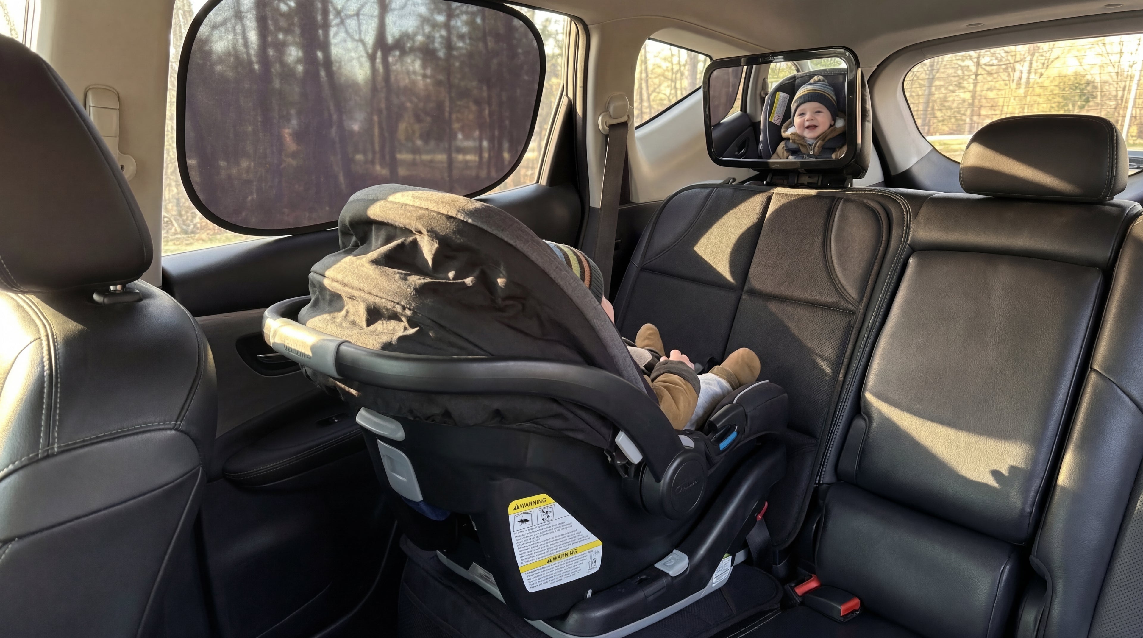 Child in a car seat inside a vehicle with a view of trees outside